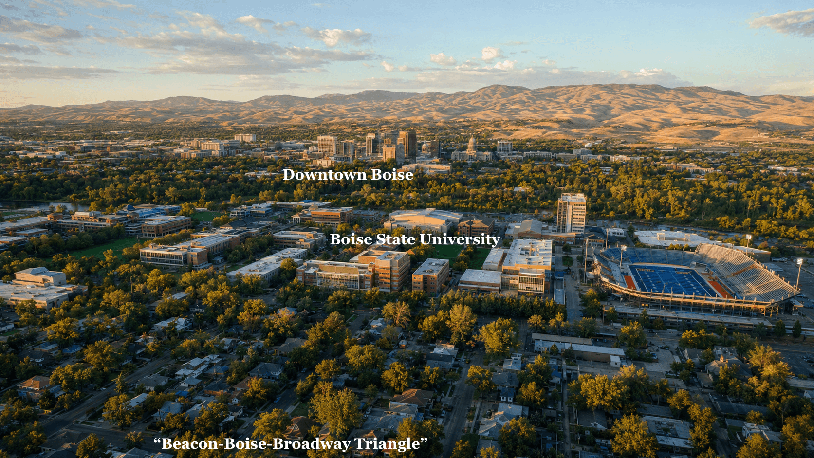 Aerial view of Boise State University campus and downtown Boise skyline against rolling foothills.
